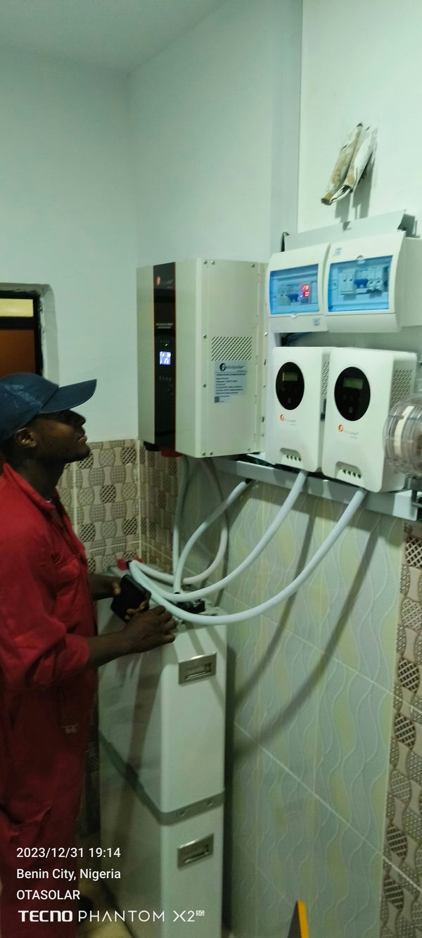 A technician from Dynotech Global Optimal Ventures installing solar inverter in a client's home